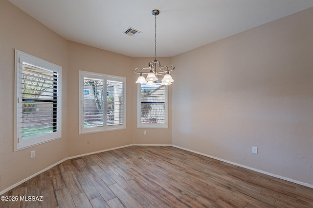 empty room featuring an inviting chandelier and light hardwood / wood-style floors