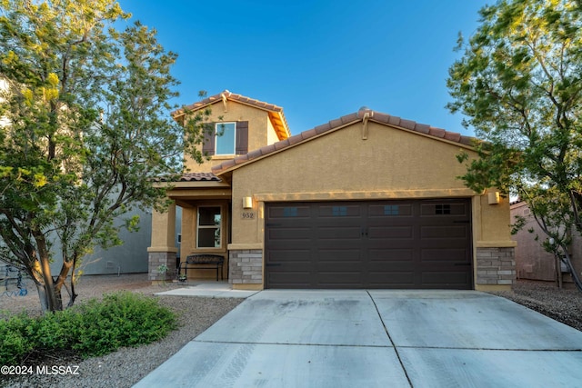 view of front facade featuring driveway, stucco siding, a garage, stone siding, and a tiled roof