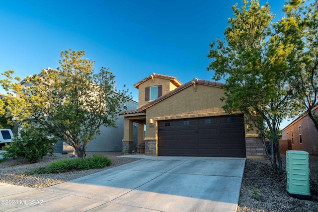 view of front of home with stucco siding, stone siding, concrete driveway, an attached garage, and a tiled roof