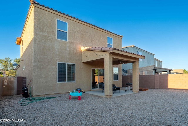 rear view of house with a tiled roof, a patio area, fence, and stucco siding