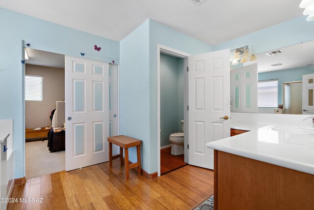 bathroom with a wealth of natural light, toilet, hardwood / wood-style flooring, and vanity