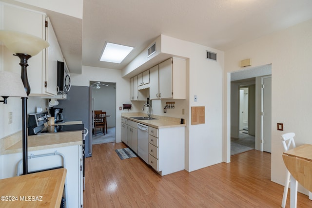 kitchen featuring stainless steel appliances, sink, light wood-type flooring, and white cabinetry