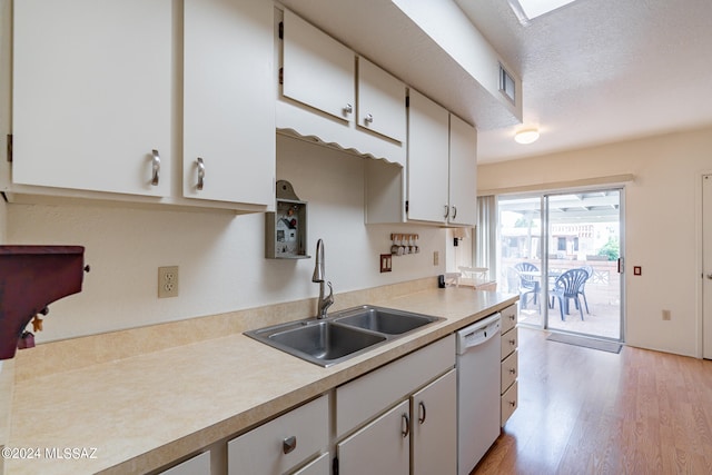 kitchen with white dishwasher, light hardwood / wood-style floors, white cabinetry, sink, and a textured ceiling