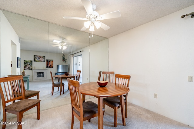 dining area featuring light carpet, a textured ceiling, and ceiling fan