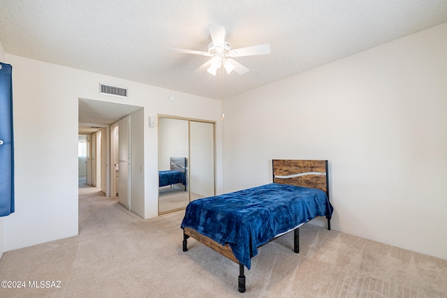 carpeted bedroom featuring a textured ceiling, ceiling fan, and a closet