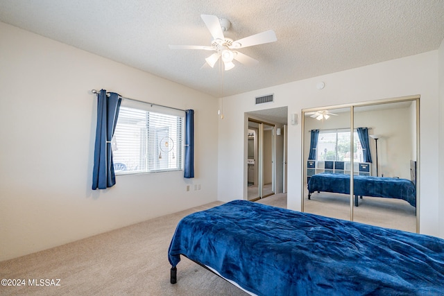 bedroom with carpet flooring, a closet, ceiling fan, and a textured ceiling