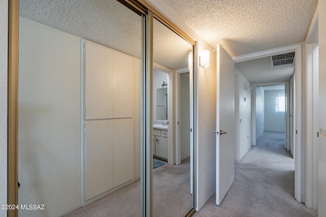 hallway featuring a textured ceiling and light carpet