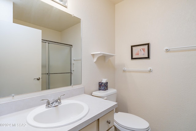 bathroom featuring vanity, toilet, and a shower with shower door