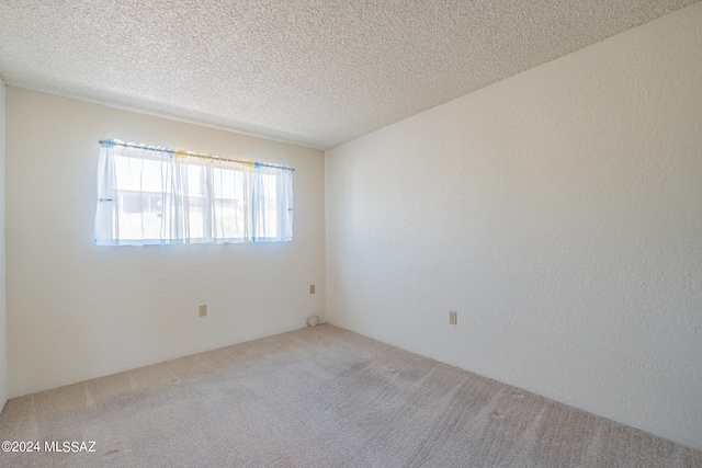 carpeted empty room featuring a textured ceiling