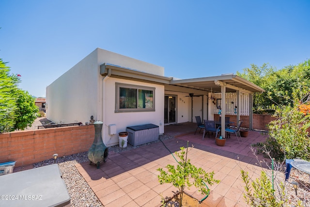 back of property featuring ceiling fan and a patio