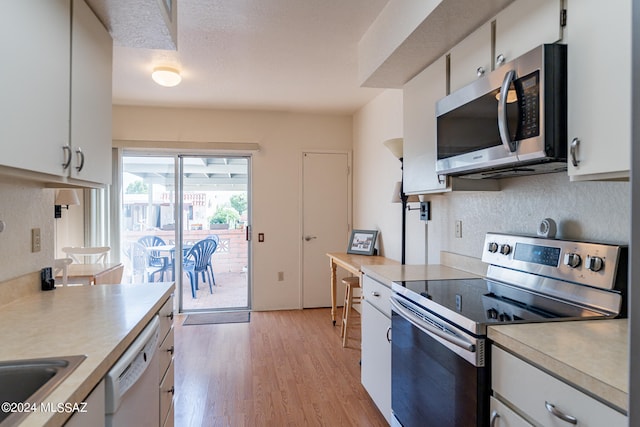 kitchen with stainless steel appliances, sink, white cabinetry, and light hardwood / wood-style flooring