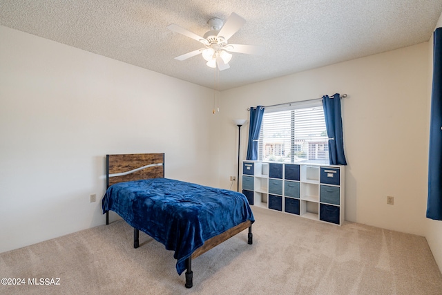 carpeted bedroom featuring a textured ceiling and ceiling fan