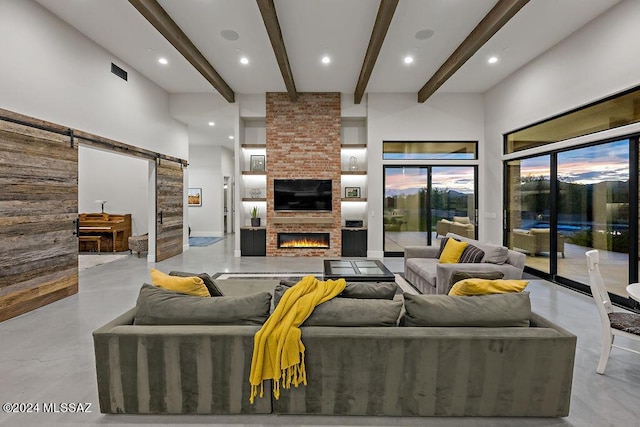 living room with visible vents, finished concrete flooring, beamed ceiling, a barn door, and a fireplace