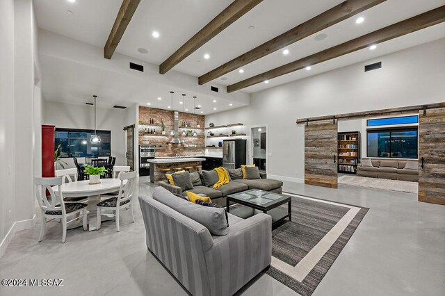 living room with a fireplace, beam ceiling, and a barn door