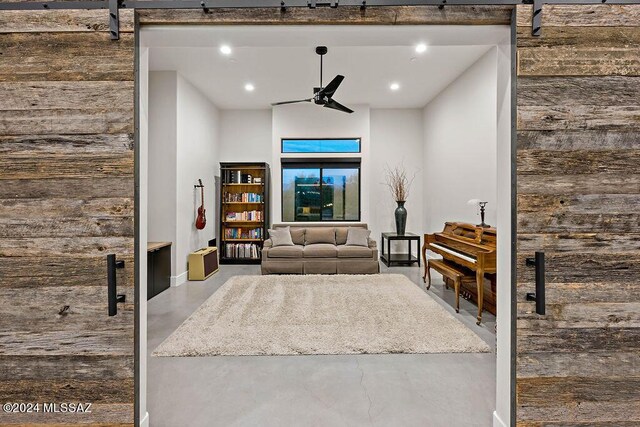 interior space with a barn door, concrete flooring, and ceiling fan