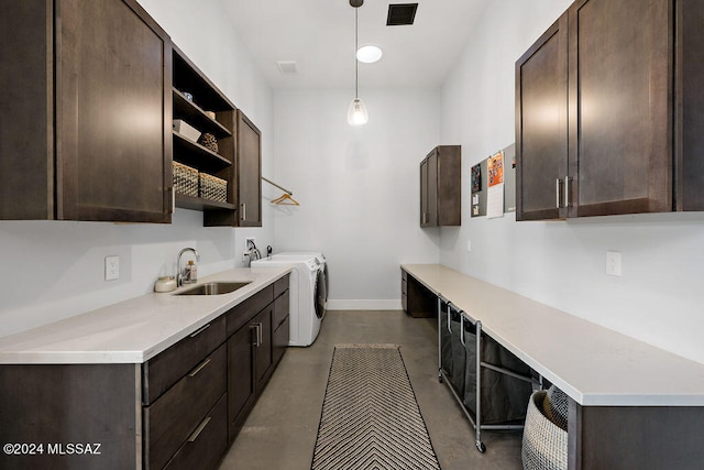 interior space featuring decorative light fixtures, washing machine and clothes dryer, concrete floors, and sink