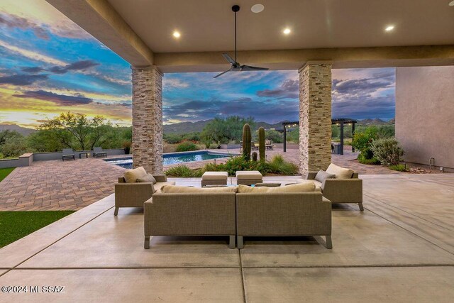 patio terrace at dusk featuring ceiling fan and an outdoor hangout area