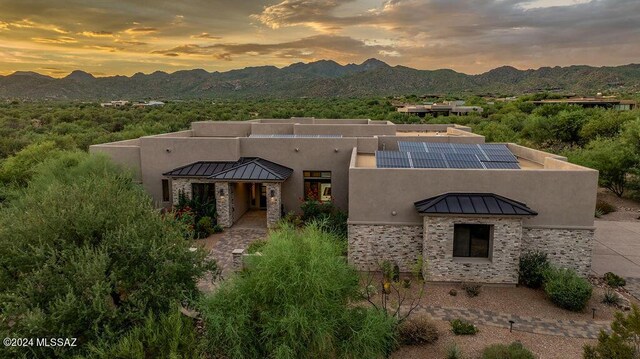 view of front of house with a mountain view, solar panels, and a patio area