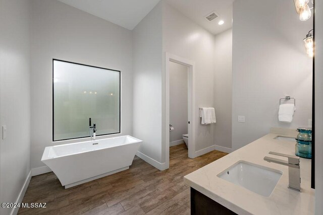 bathroom with vanity, toilet, wood-type flooring, and a washtub