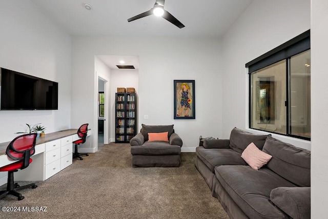 carpeted living area with visible vents, baseboards, a ceiling fan, and built in desk