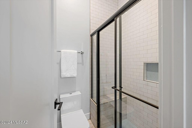 bathroom featuring toilet and a stall shower