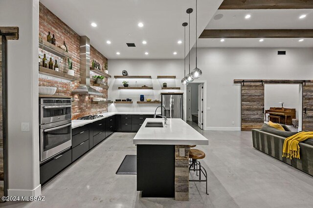 kitchen featuring pendant lighting, appliances with stainless steel finishes, tasteful backsplash, sink, and a barn door