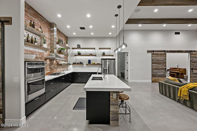 kitchen with open shelves, a sink, a barn door, appliances with stainless steel finishes, and light countertops