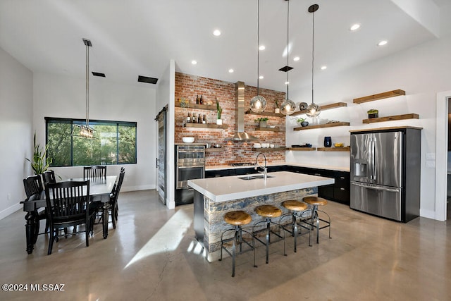 kitchen featuring a kitchen island with sink, concrete floors, stainless steel appliances, sink, and a breakfast bar area