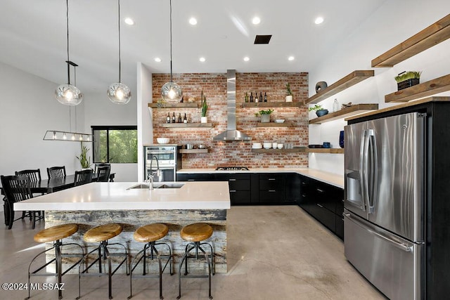 kitchen featuring dark cabinetry, open shelves, wall chimney range hood, and stainless steel appliances