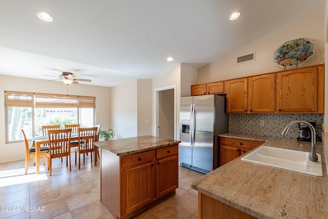 kitchen featuring lofted ceiling, a kitchen island, sink, and stainless steel fridge with ice dispenser