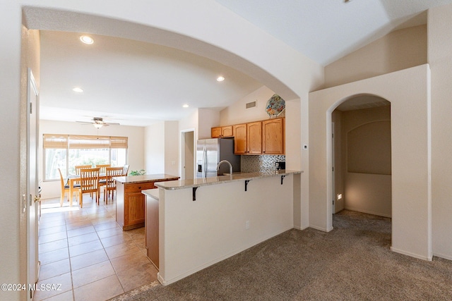 kitchen featuring kitchen peninsula, ceiling fan, stainless steel fridge with ice dispenser, vaulted ceiling, and light colored carpet