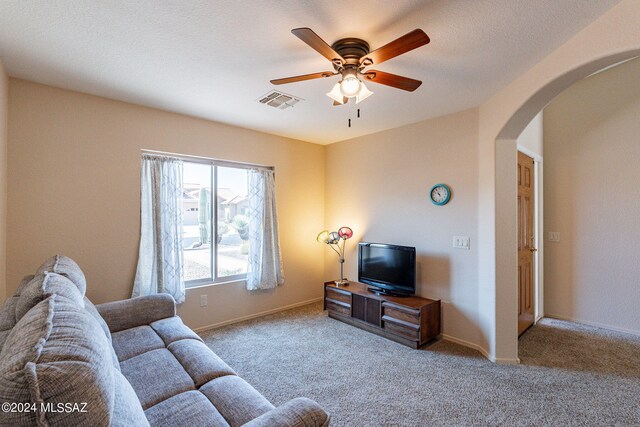 carpeted living room with ceiling fan and a textured ceiling