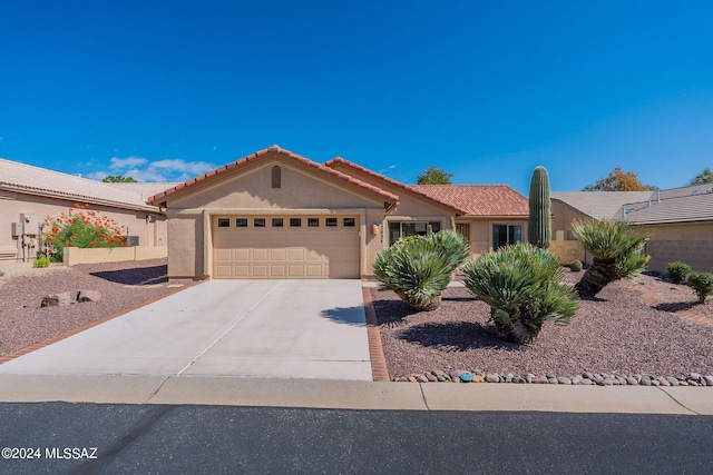 view of front of house featuring driveway, stucco siding, a tile roof, and a garage
