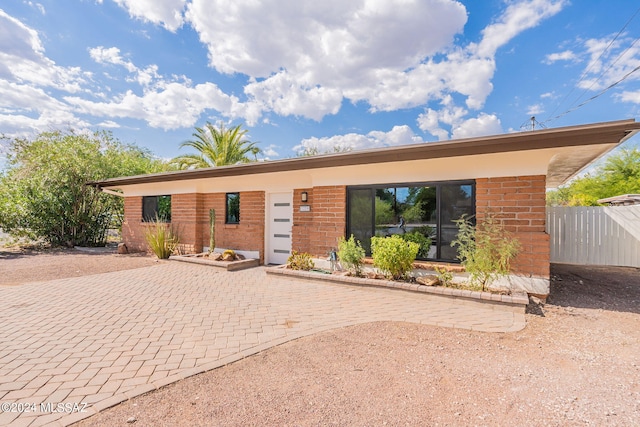 view of front of home featuring brick siding and fence