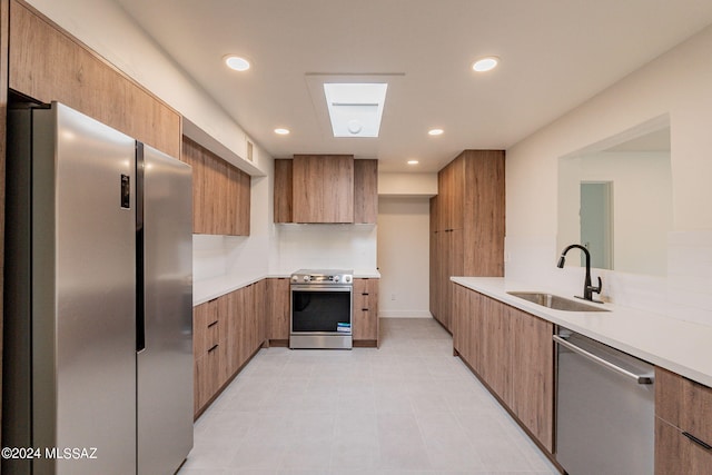 kitchen with a sink, light countertops, wall chimney range hood, appliances with stainless steel finishes, and modern cabinets