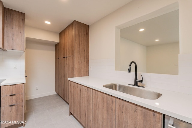 kitchen featuring tasteful backsplash, modern cabinets, light countertops, and a sink