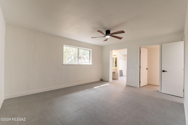 unfurnished bedroom with a walk in closet, ceiling fan, baseboards, and ensuite bathroom