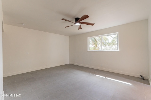 tiled spare room featuring a ceiling fan and baseboards