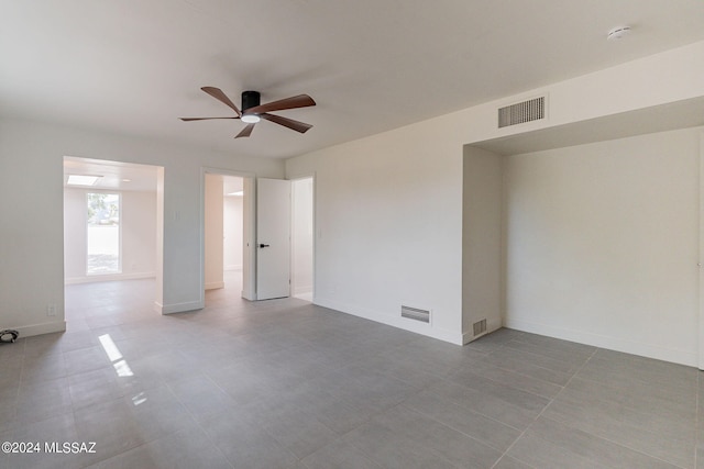 unfurnished room with ceiling fan, visible vents, and baseboards