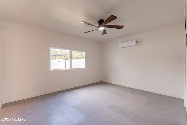 spare room featuring a ceiling fan, an AC wall unit, and baseboards