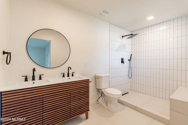 bathroom with double vanity, tiled shower, toilet, tile patterned flooring, and a sink