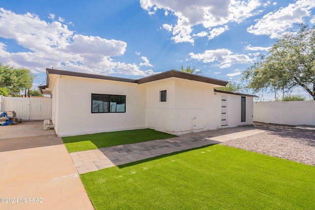 view of front of home with a front yard, fence, a patio, and stucco siding