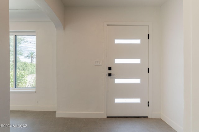 foyer entrance with arched walkways and baseboards