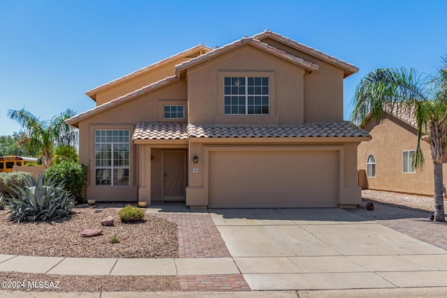 mediterranean / spanish house with an attached garage, concrete driveway, stucco siding, and a tiled roof