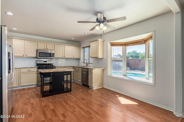 kitchen featuring appliances with stainless steel finishes, decorative backsplash, a ceiling fan, and a sink