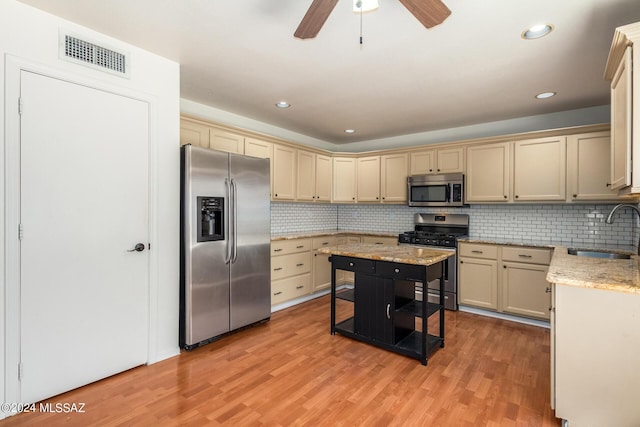 kitchen with stainless steel appliances, light wood-style floors, ceiling fan, a sink, and visible vents