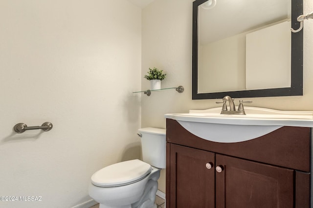 bathroom with toilet, vanity, and baseboards