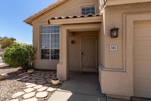 property entrance with a tile roof and stucco siding