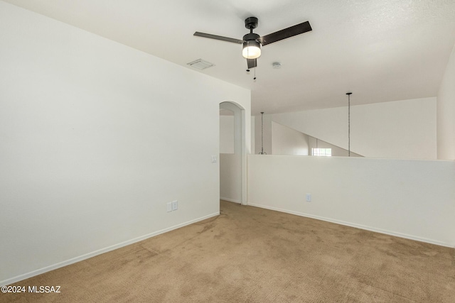 spare room with arched walkways, light carpet, ceiling fan, baseboards, and visible vents