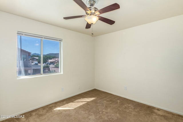 carpeted spare room with baseboards and ceiling fan